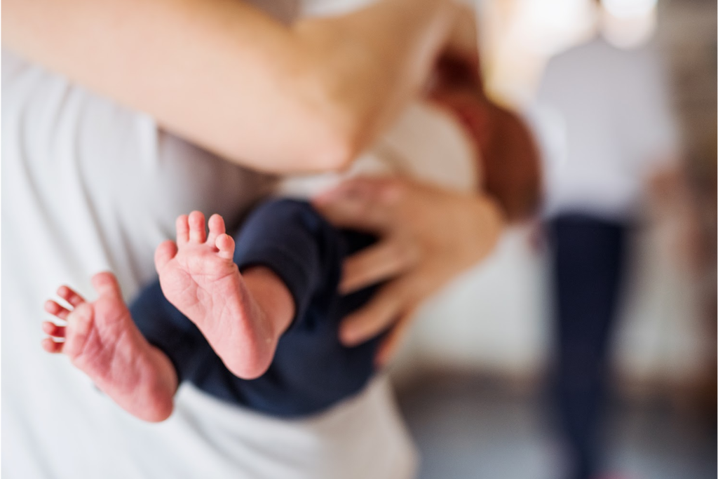 Baby being held, tiny feet visible.