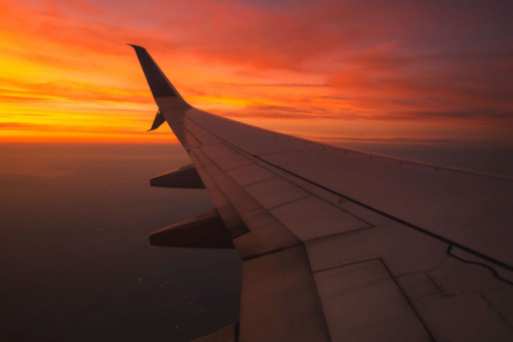 Airplane wing against vibrant sunset